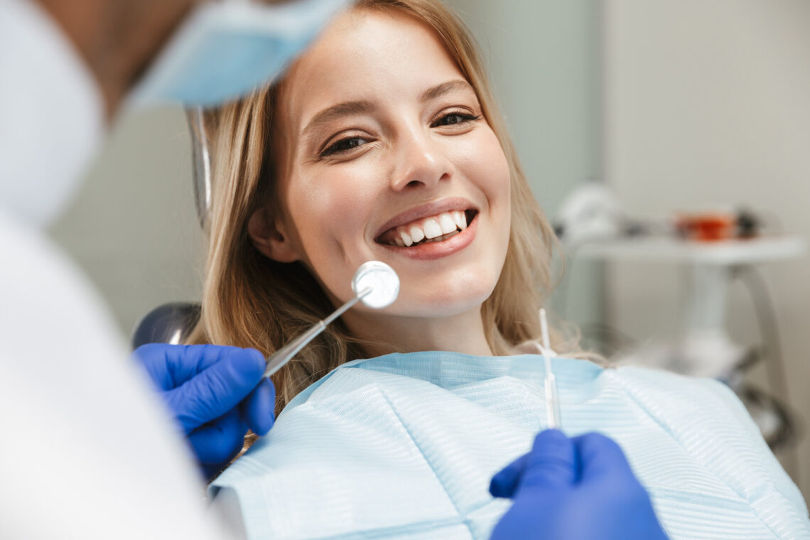 Bild einer zufriedenen jungen Frau, die im Behandlungsstuhl beim Zahnarzt sitzt
