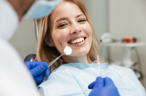 Bild einer zufriedenen jungen Frau, die im Behandlungsstuhl beim Zahnarzt sitzt