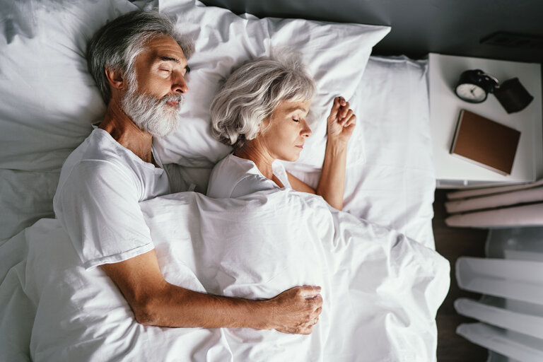 Älteres Ehepaar, das zusammen im Bett schläft.