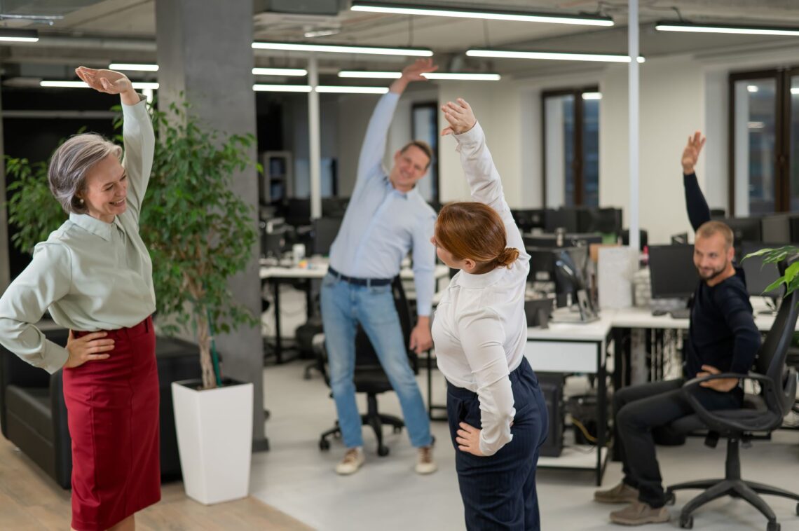 Mitarbeitende machen Gymnastik im Büro